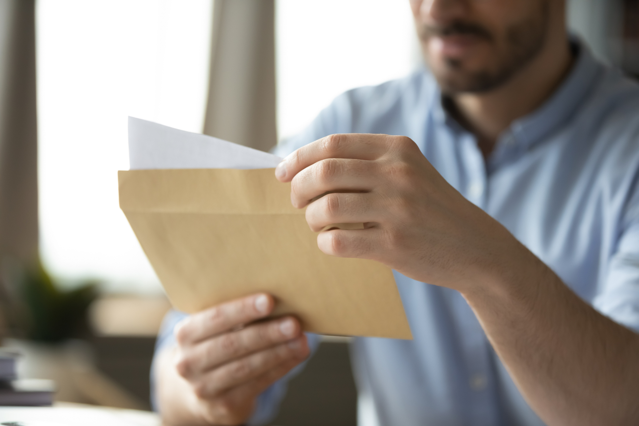 Formal paperwork. Close up shot paper letter in postal envelop in young male hands. Legal financial correspondence official institution response to request sending receiving feedback by mail concept