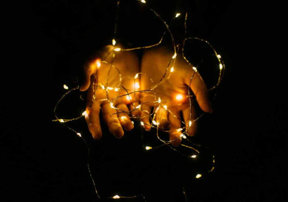 Christmas lights with warm shining closeup. Holding garland in hands.