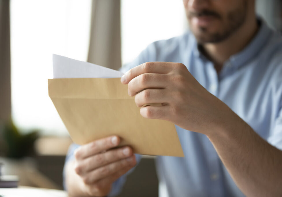 Formal paperwork. Close up shot paper letter in postal envelop in young male hands. Legal financial correspondence official institution response to request sending receiving feedback by mail concept