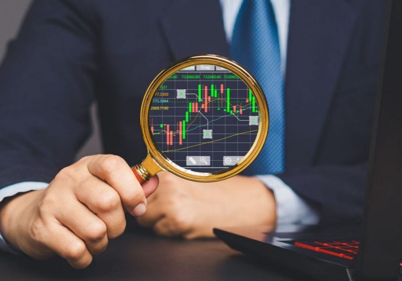 Stock exchange market analysis. A businessman or trader uses a magnifying glass to examine a stock graph on a virtual screen. concept of business and financial investment.