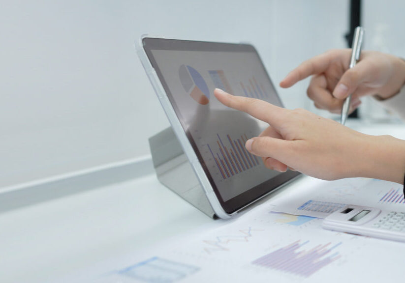 close up businesswoman hand point on digital tablet device with dashboard screen for ask and consulting with businessman partner for investment concept